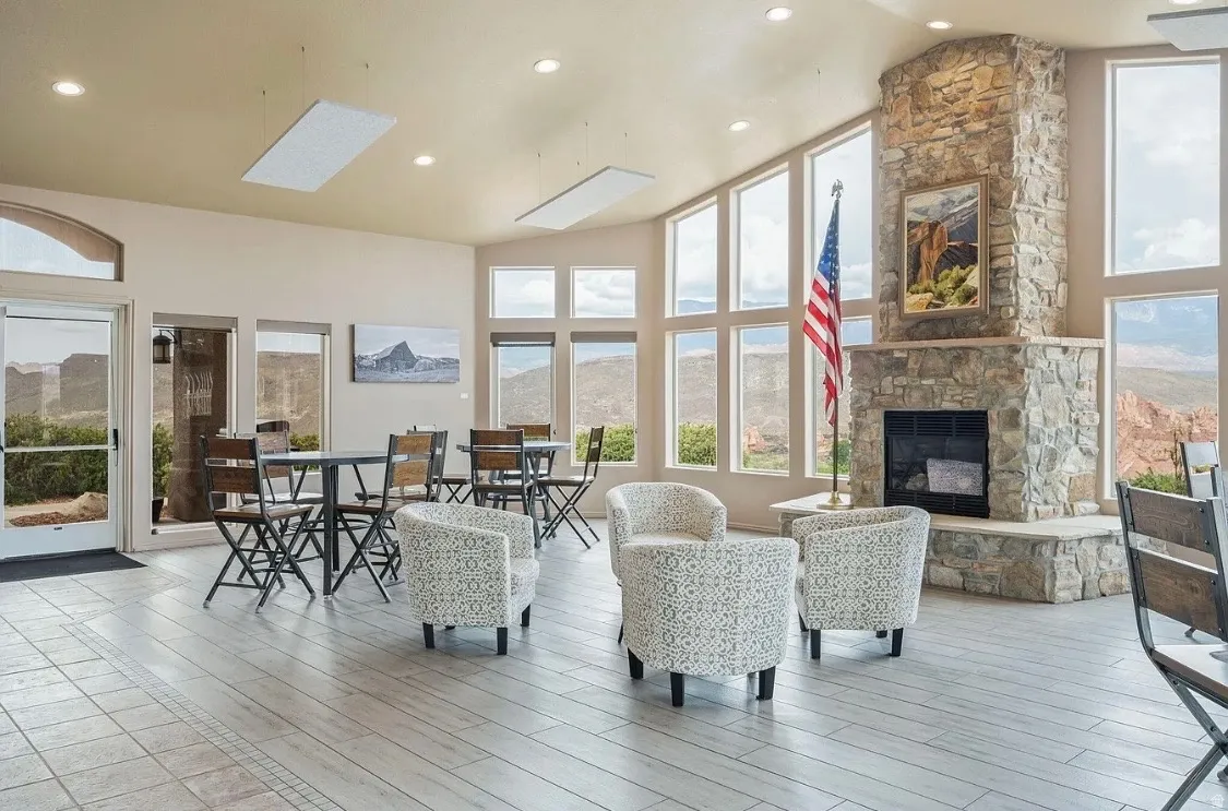 Spacious interior featuring a stone-clad fireplace, large picture windows, recessed lighting, ceiling-mounted panels, and light-toned tile flooring