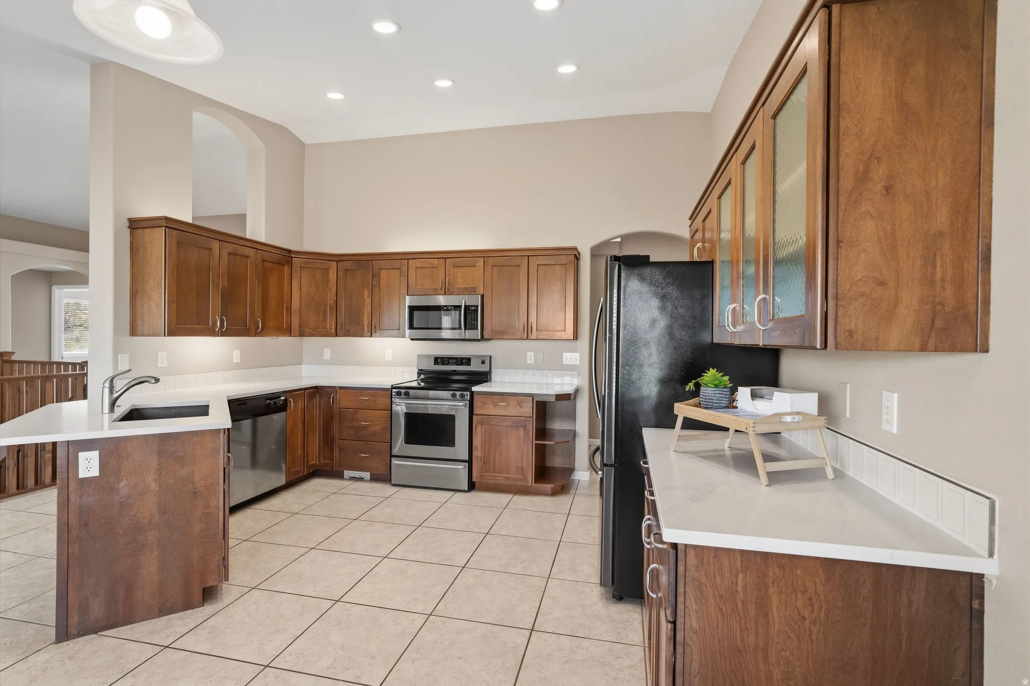 Spacious kitchen featuring rich wood cabinetry, stainless steel appliances, light-toned countertops, and a white subway tile backsplash