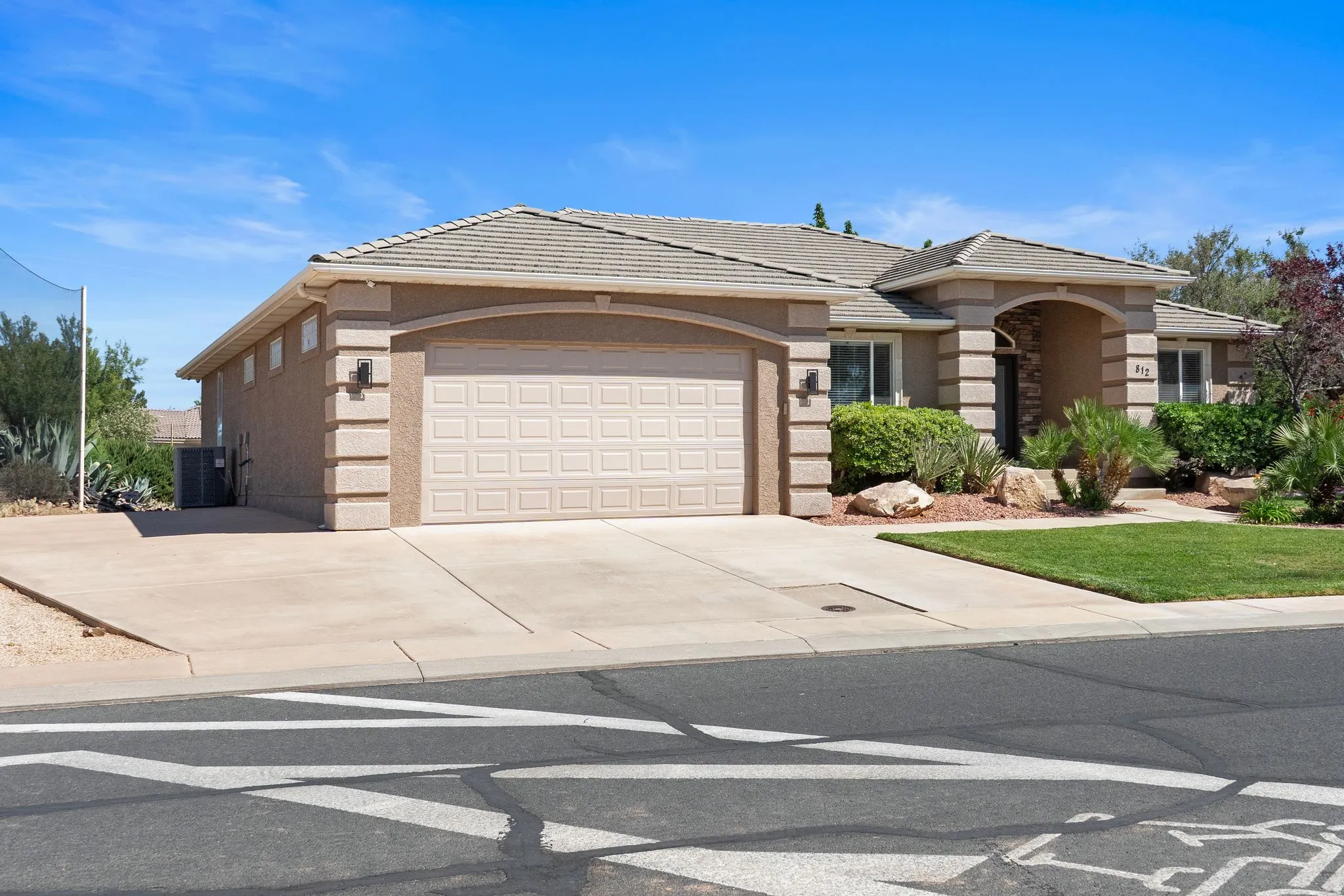 Stucco-clad residence featuring an attached two-car garage, concrete driveway, and a tiled roof