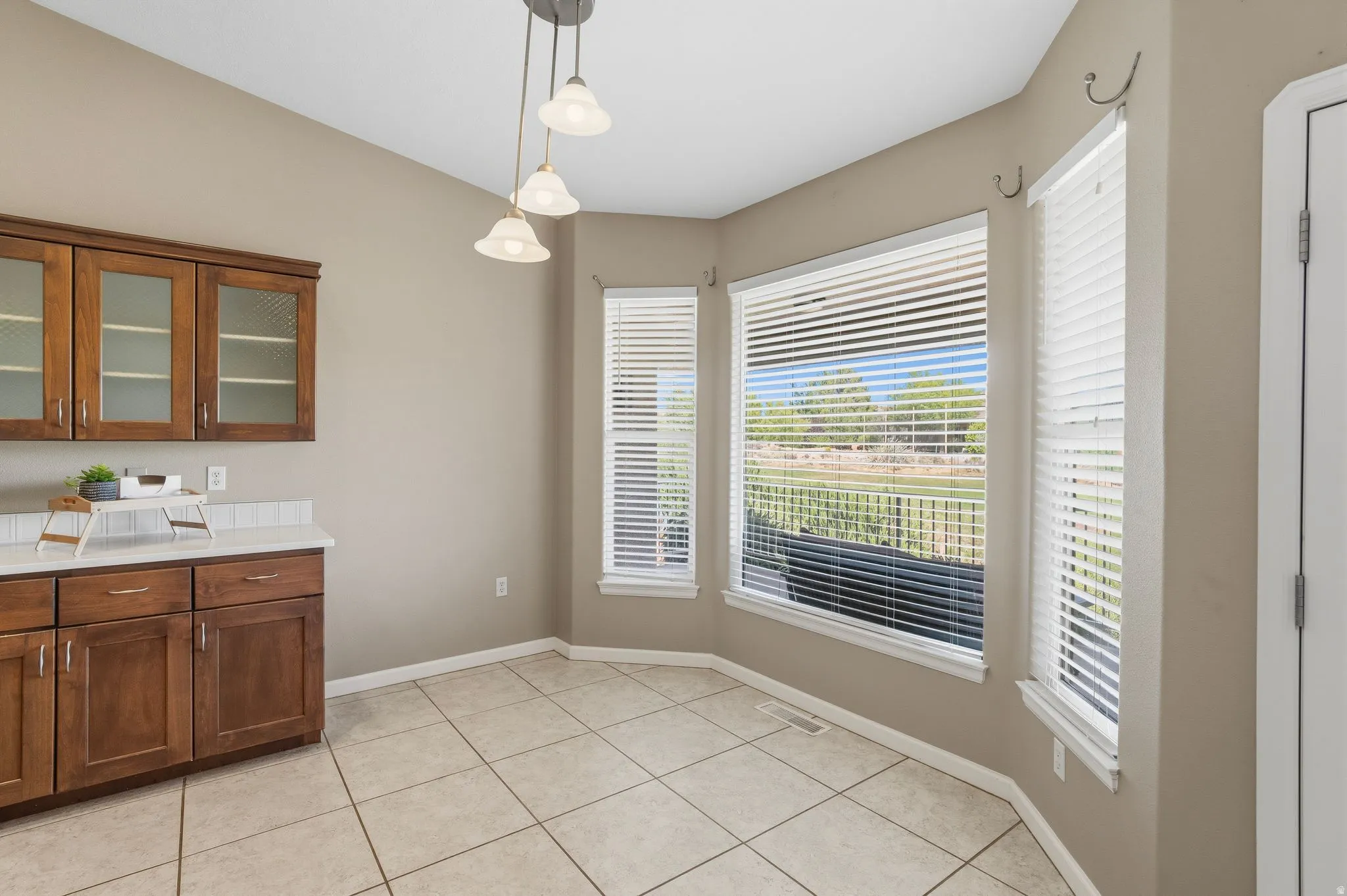 Bay window with multiple windows, ceramic tile flooring, and pendent lighting
