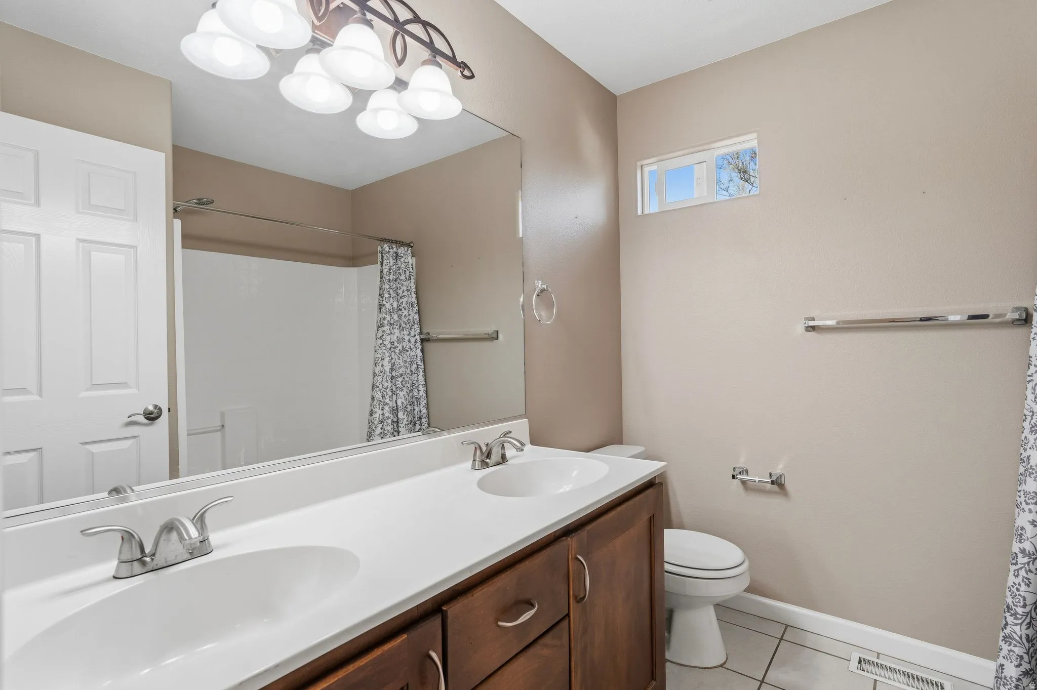 Bathroom featuring a dual-sink vanity with white countertop, dark wood-finish cabinetry, and brushed nickel fixtures