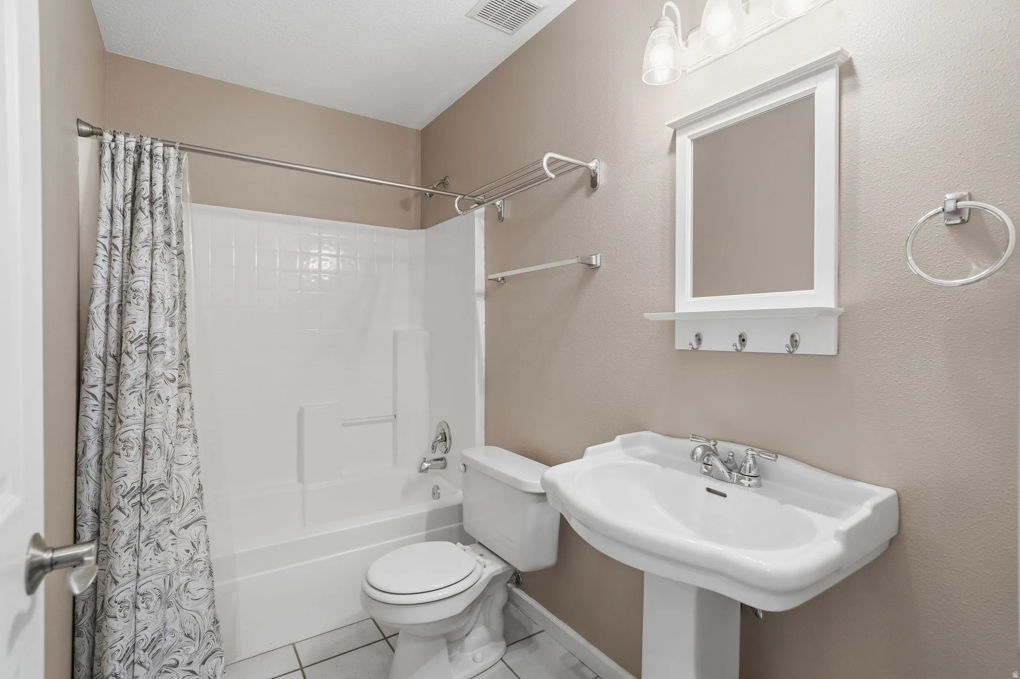 Bathroom featuring a white pedestal sink with chrome fixtures, a mirrored vanity with integrated hooks, and a white toilet