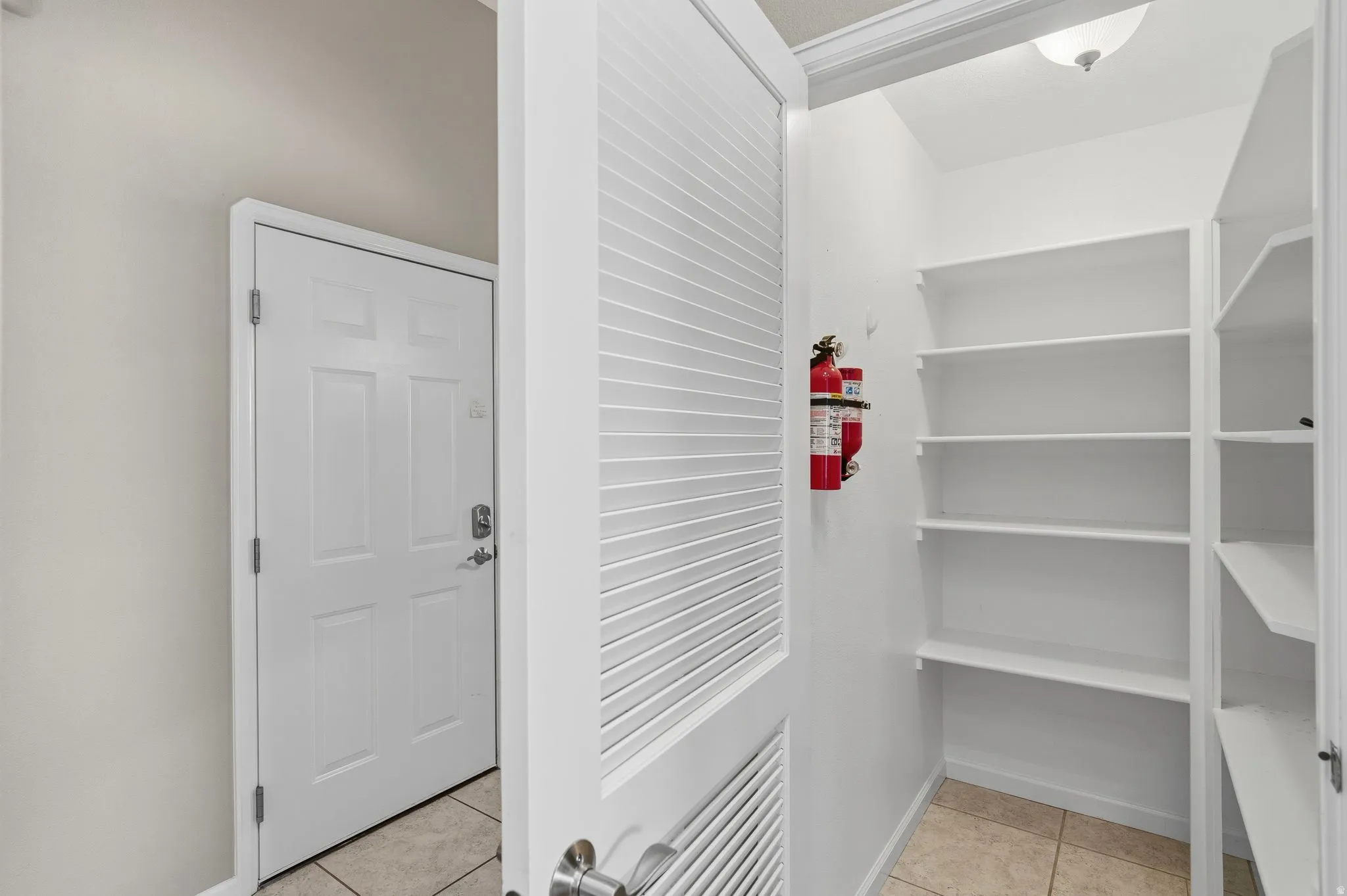 Built-in shelving for ample storage, neutral tone walls, recessed lighting, and tile flooring