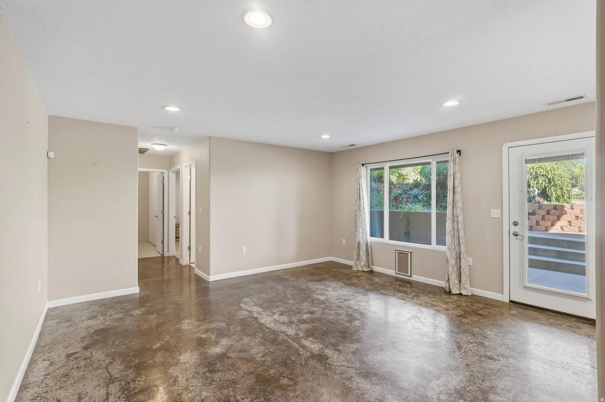 Spacious living area featuring polished concrete flooring, recessed lighting, and a large picture window