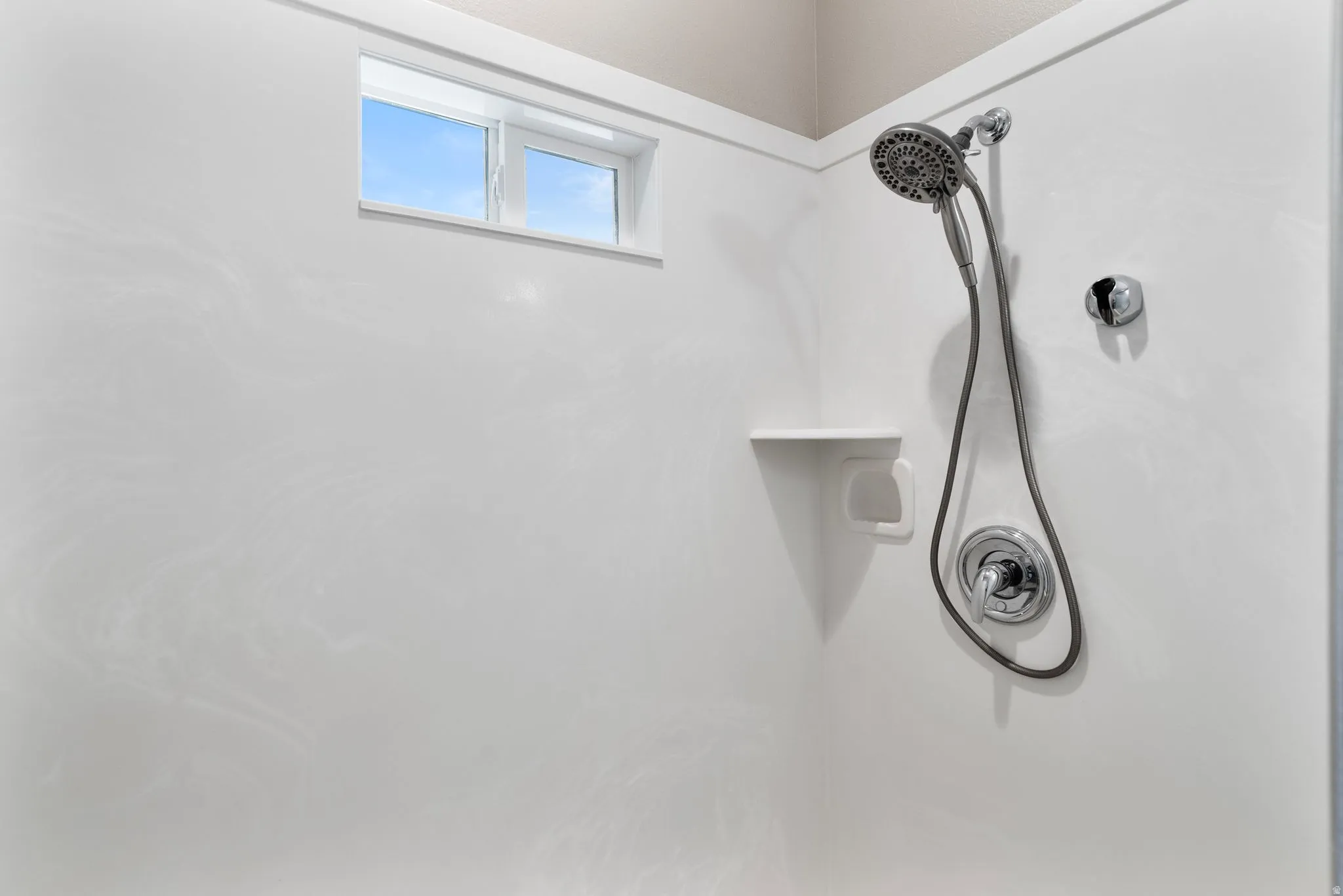 Shower with white paneling and a high-set window
