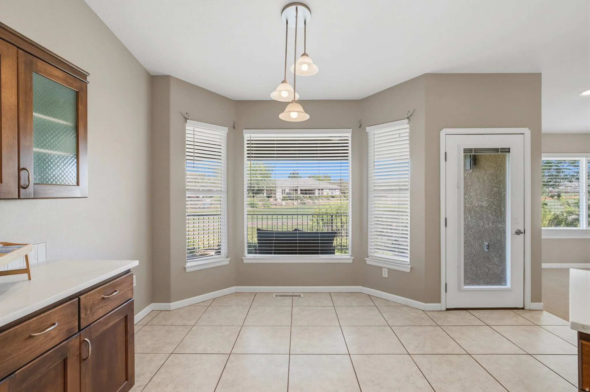 Bay window with multiple panes, ceramic tile flooring, pendulum lighting fixture, white trim, and a glass-paneled door