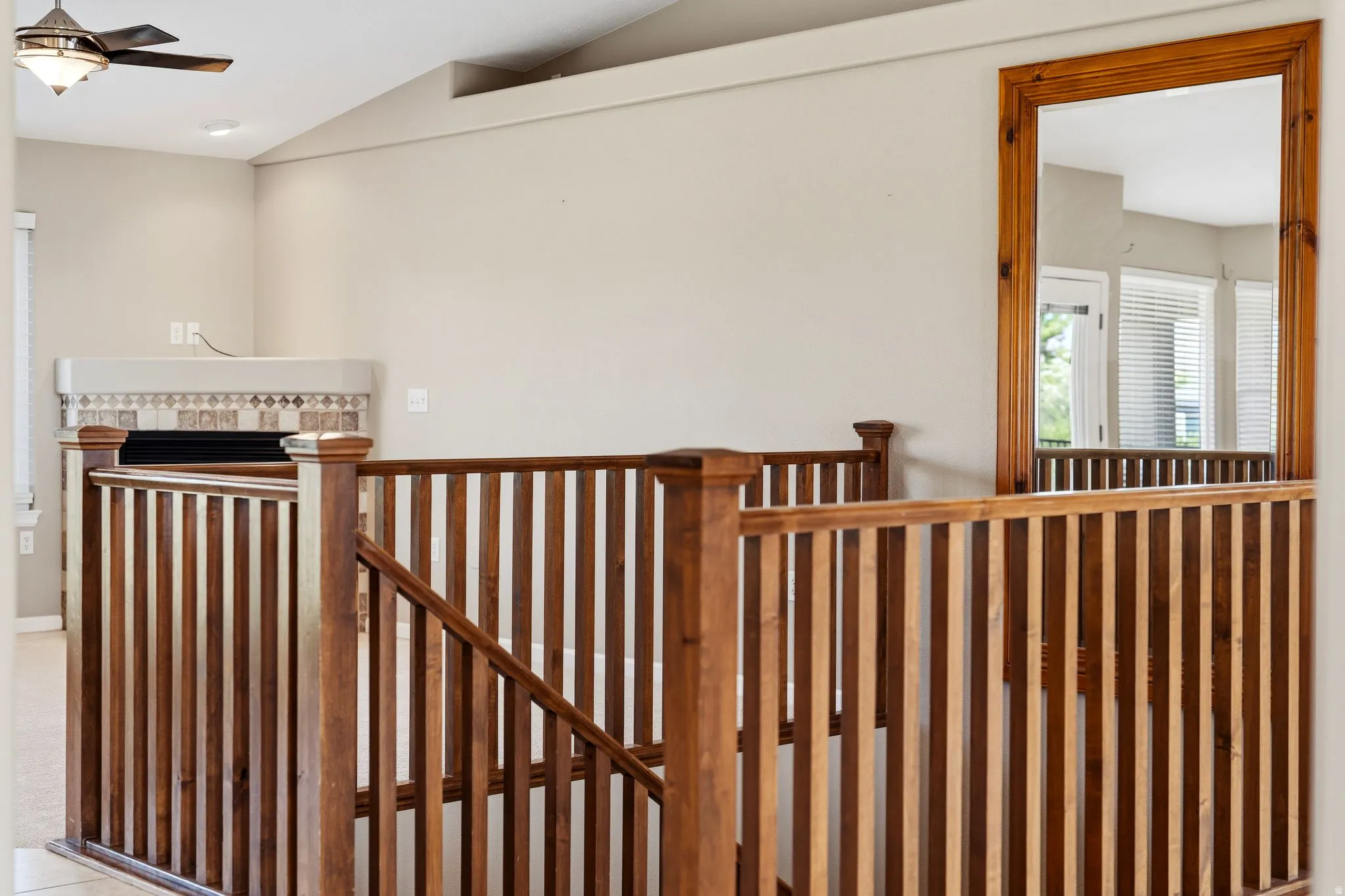 Wood-finish staircase railing leading to an upper level, featuring light neutral wall paint