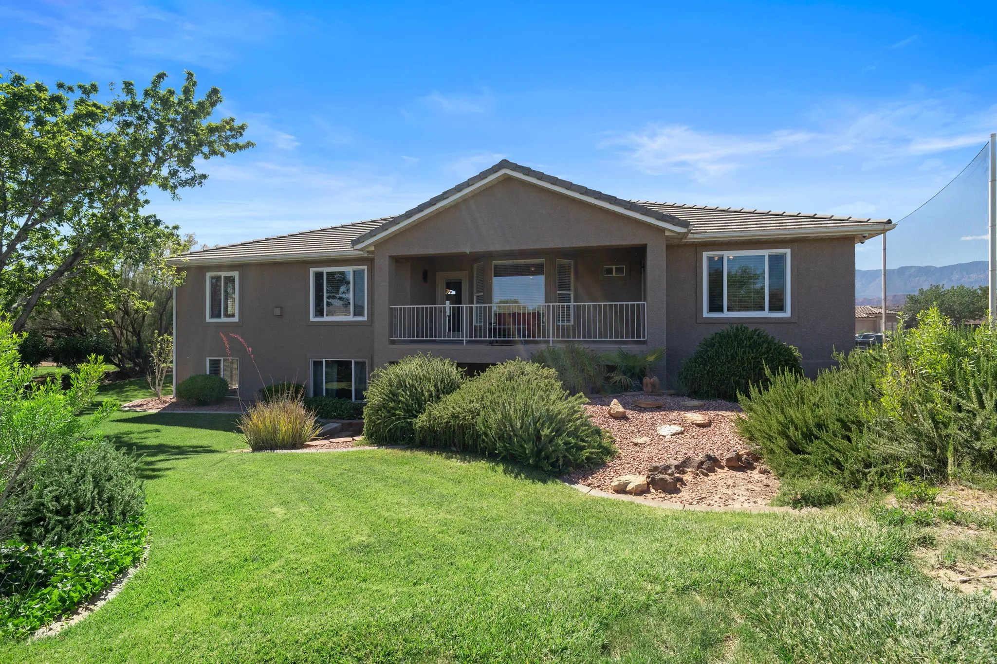 Spacious multi-level property featuring a large backyard with extensive lawn and mature landscaping