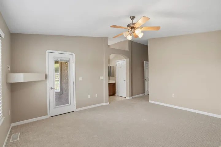Spacious room with neutral carpeting and walls, featuring a glass-paneled door