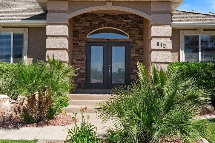 Entryway featuring stone veneer accents, arched transom window, and double glass-paneled doors
