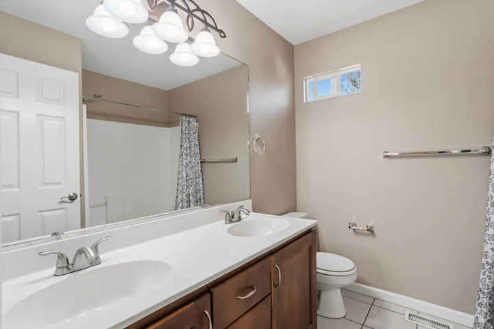 Bathroom featuring a dual-sink vanity with white countertop, dark wood-finish cabinetry, and brushed nickel fixtures