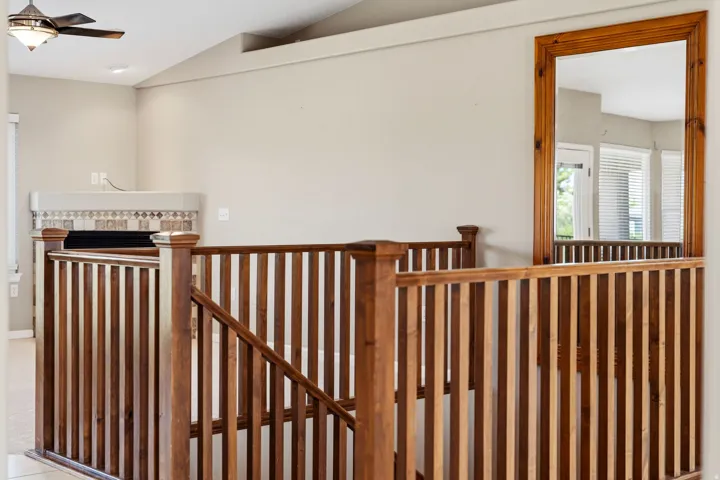 Wood-finish staircase railing leading to an upper level, featuring light neutral wall paint