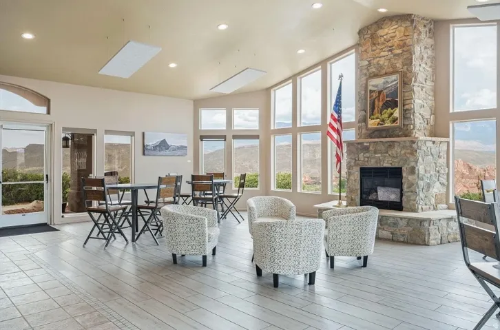 Spacious interior featuring a stone-clad fireplace, large picture windows, recessed lighting, ceiling-mounted panels, and light-toned tile flooring