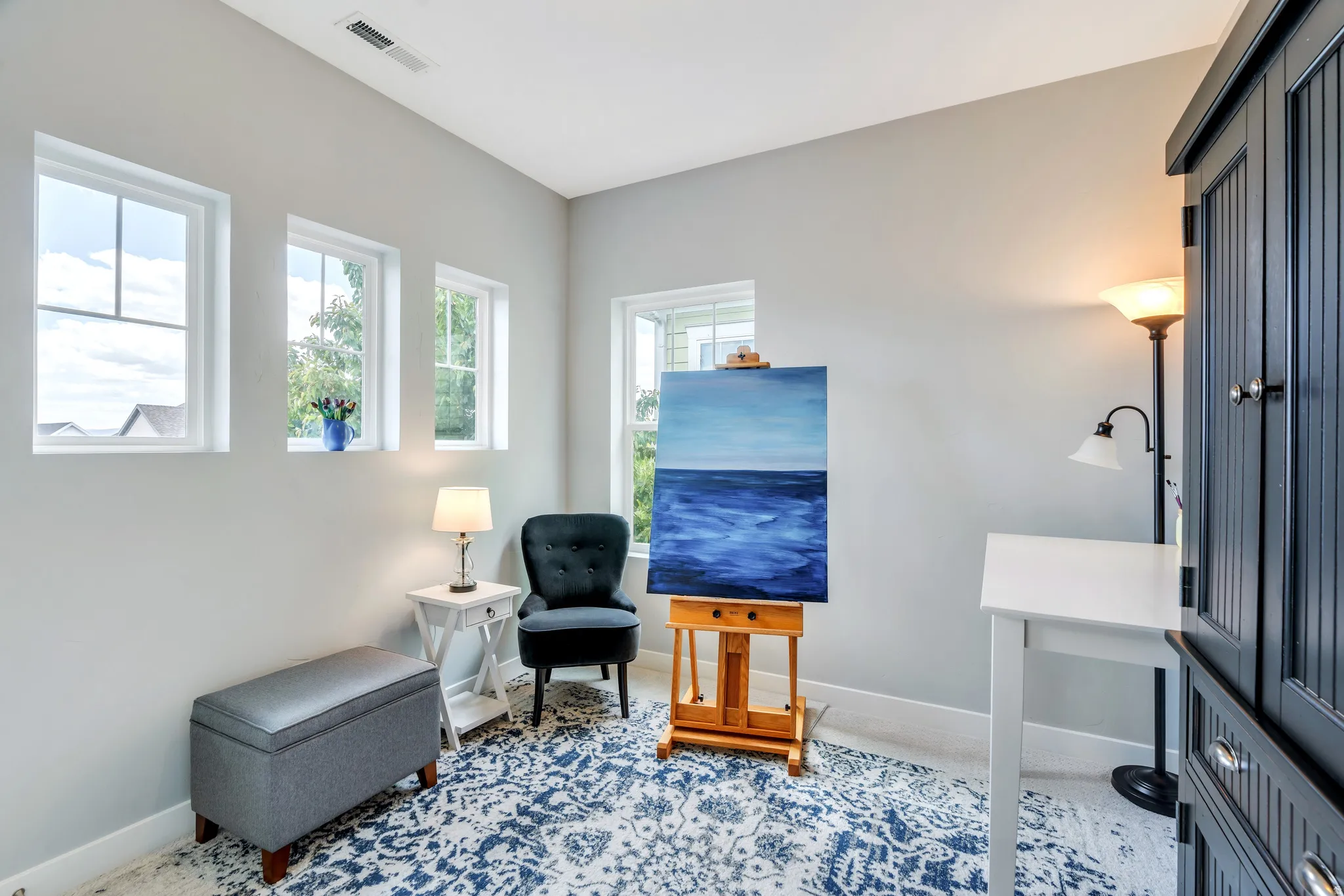 Room featuring multiple windows, light gray walls, white trim, and a patterned area rug