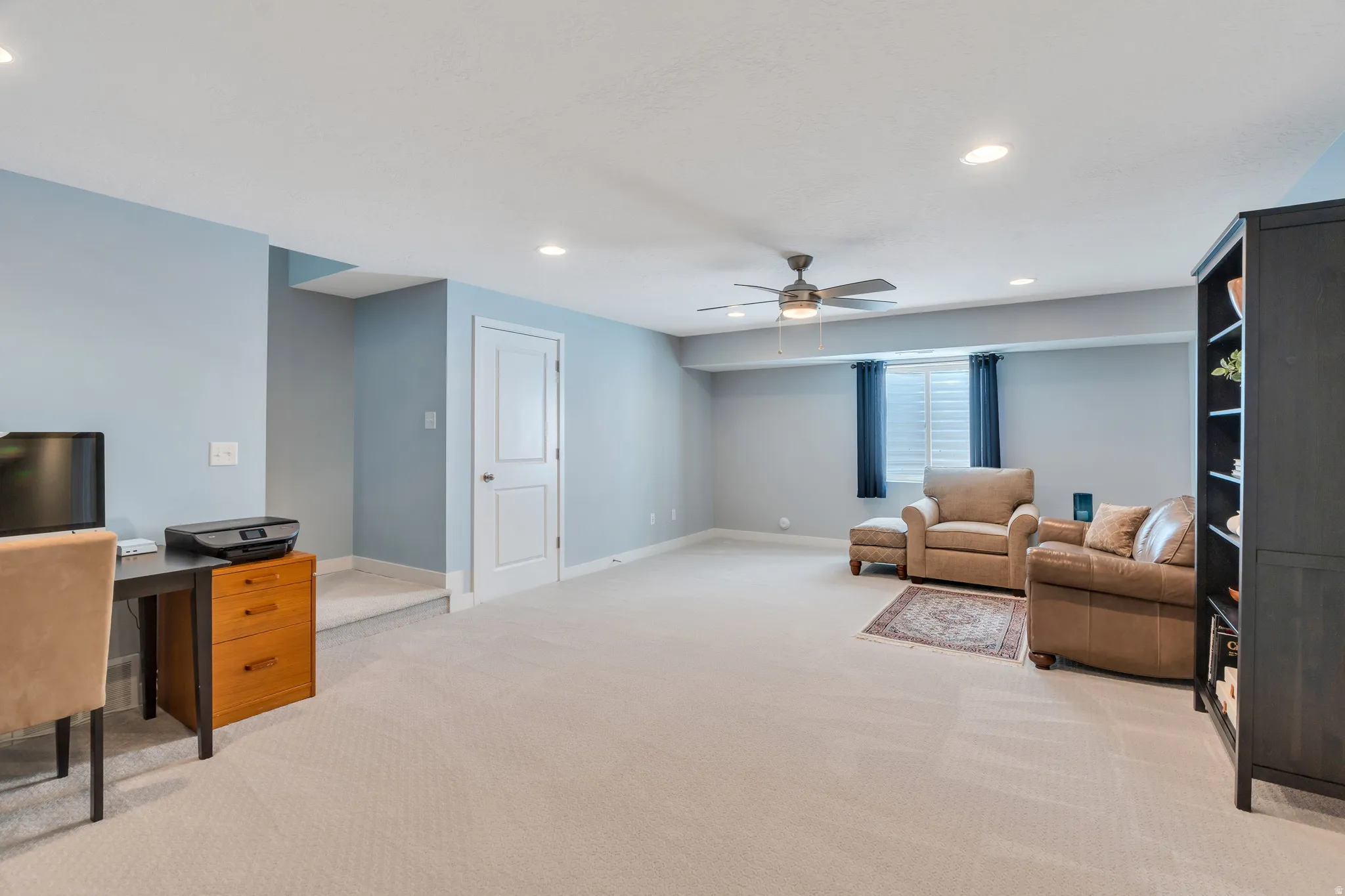 Spacious room featuring light blue walls and neutral carpeting