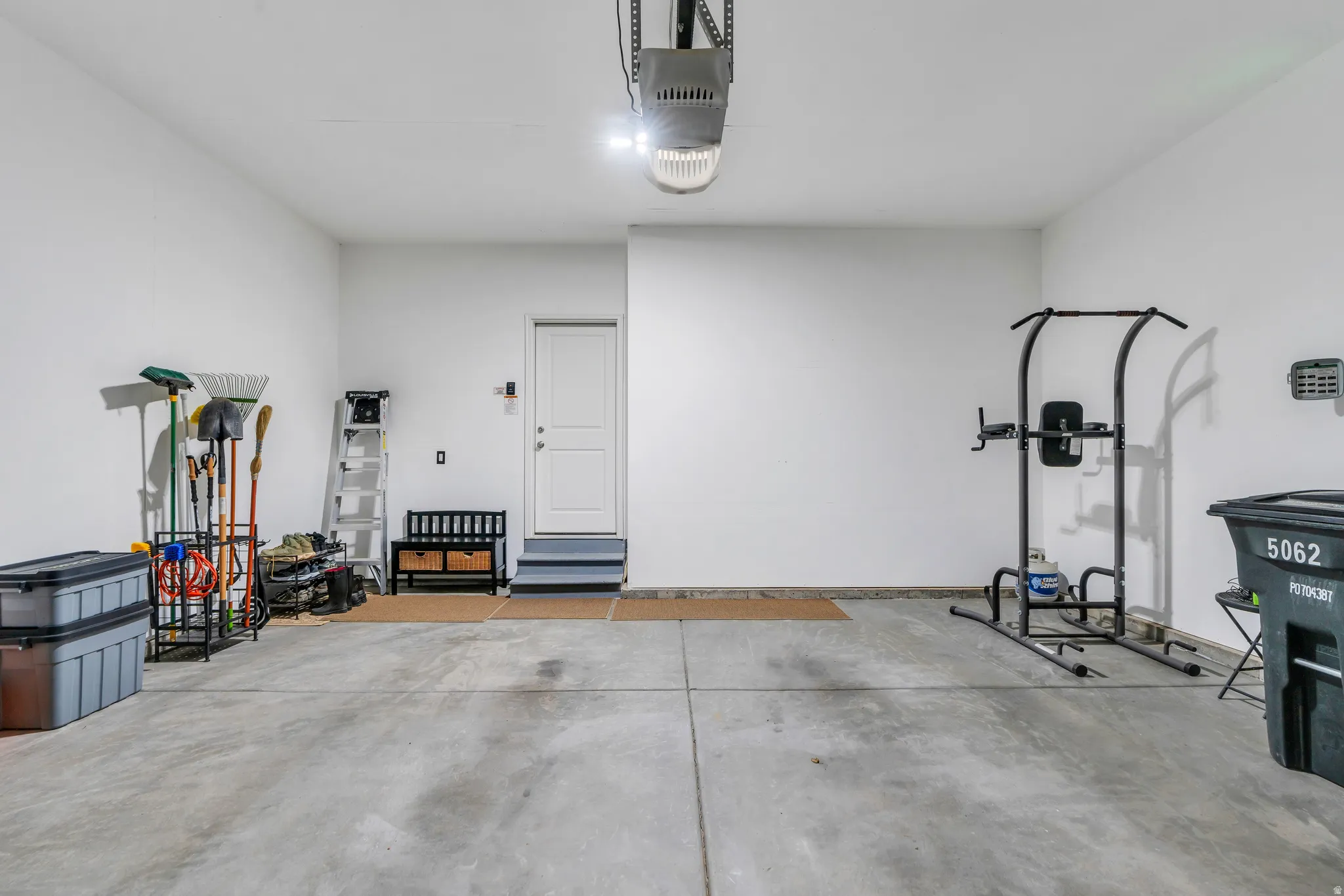 Spacious garage featuring a concrete floor, bright overhead lighting, and an internal access door