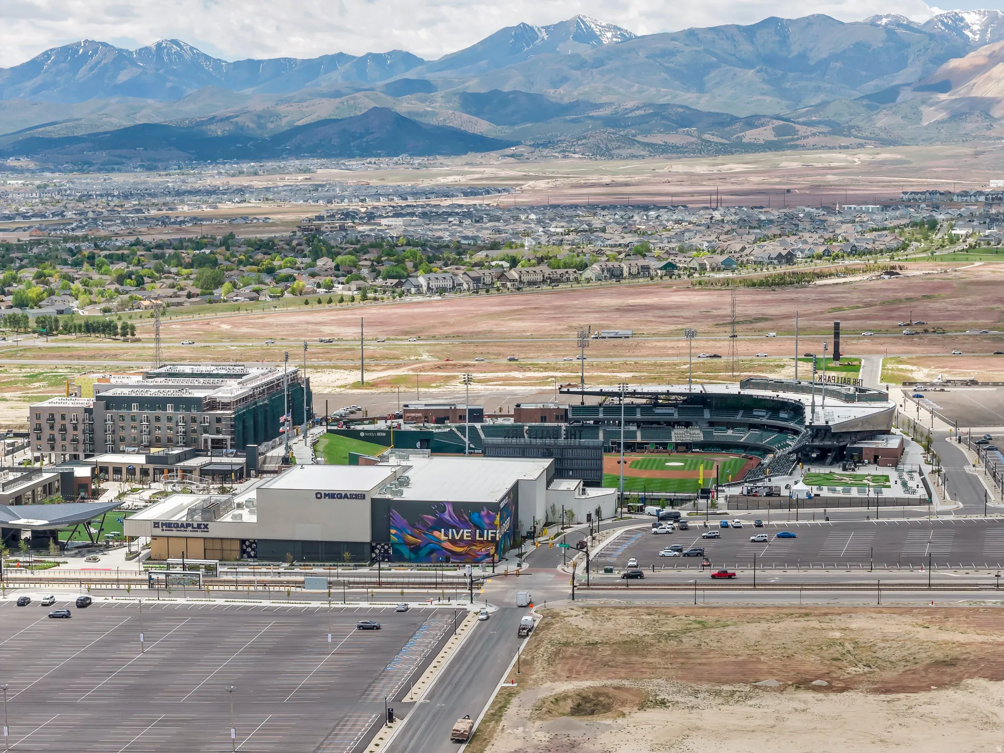 Aerial perspective showcasing a stadium complex with a hotel, entertainment venue, and expansive parking areas