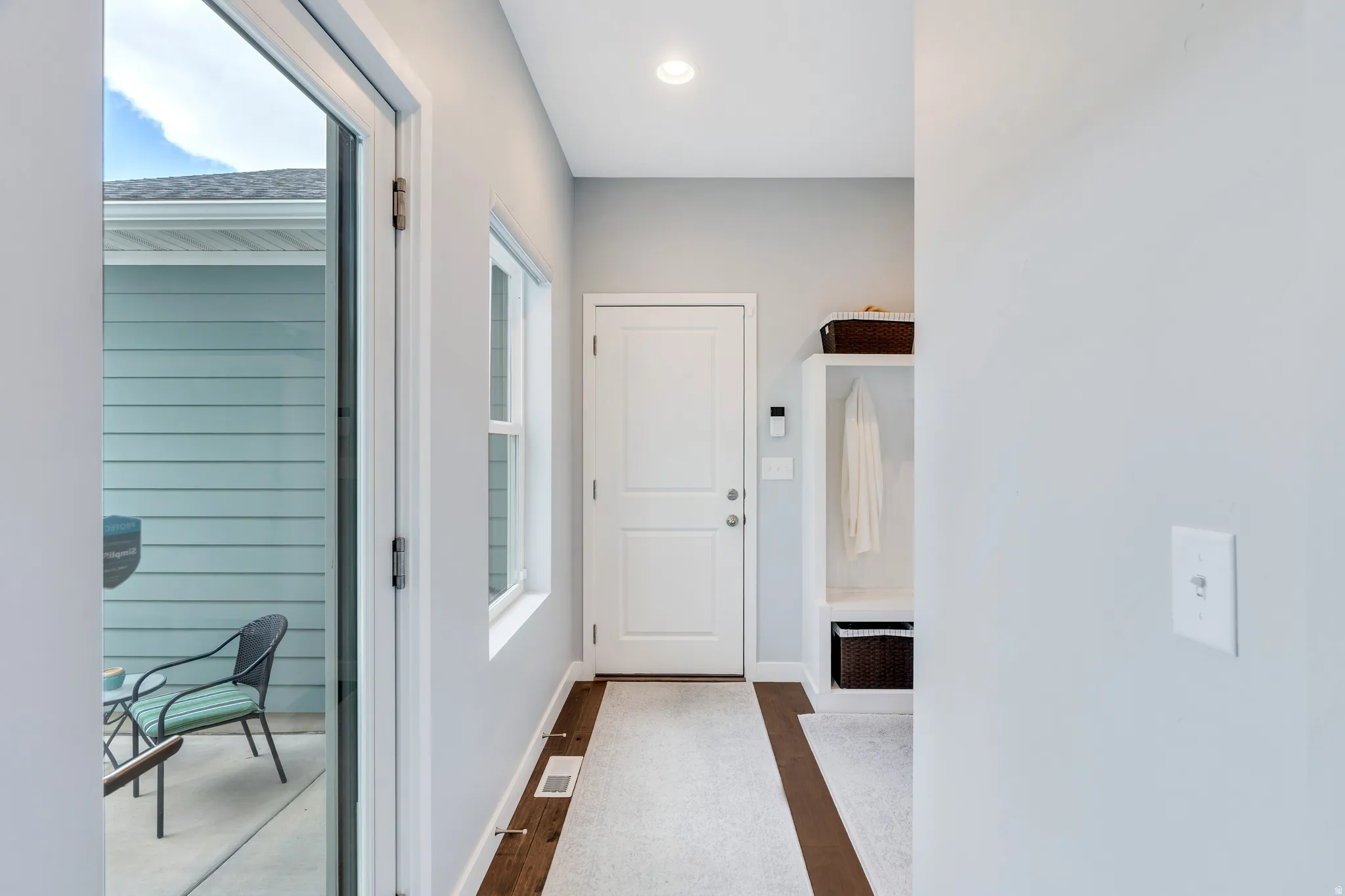 Entryway featuring a built-in mudroom bench with shelving, a white paneled door, and a sliding glass door