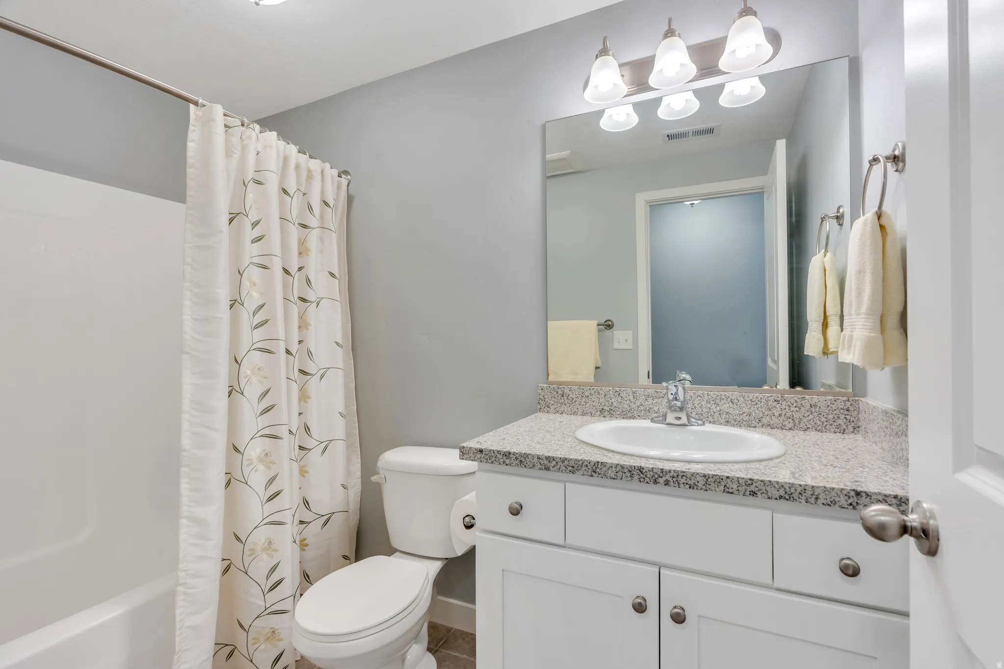 Bathroom featuring a white vanity with a speckled countertop, undermount sink, and chrome faucet