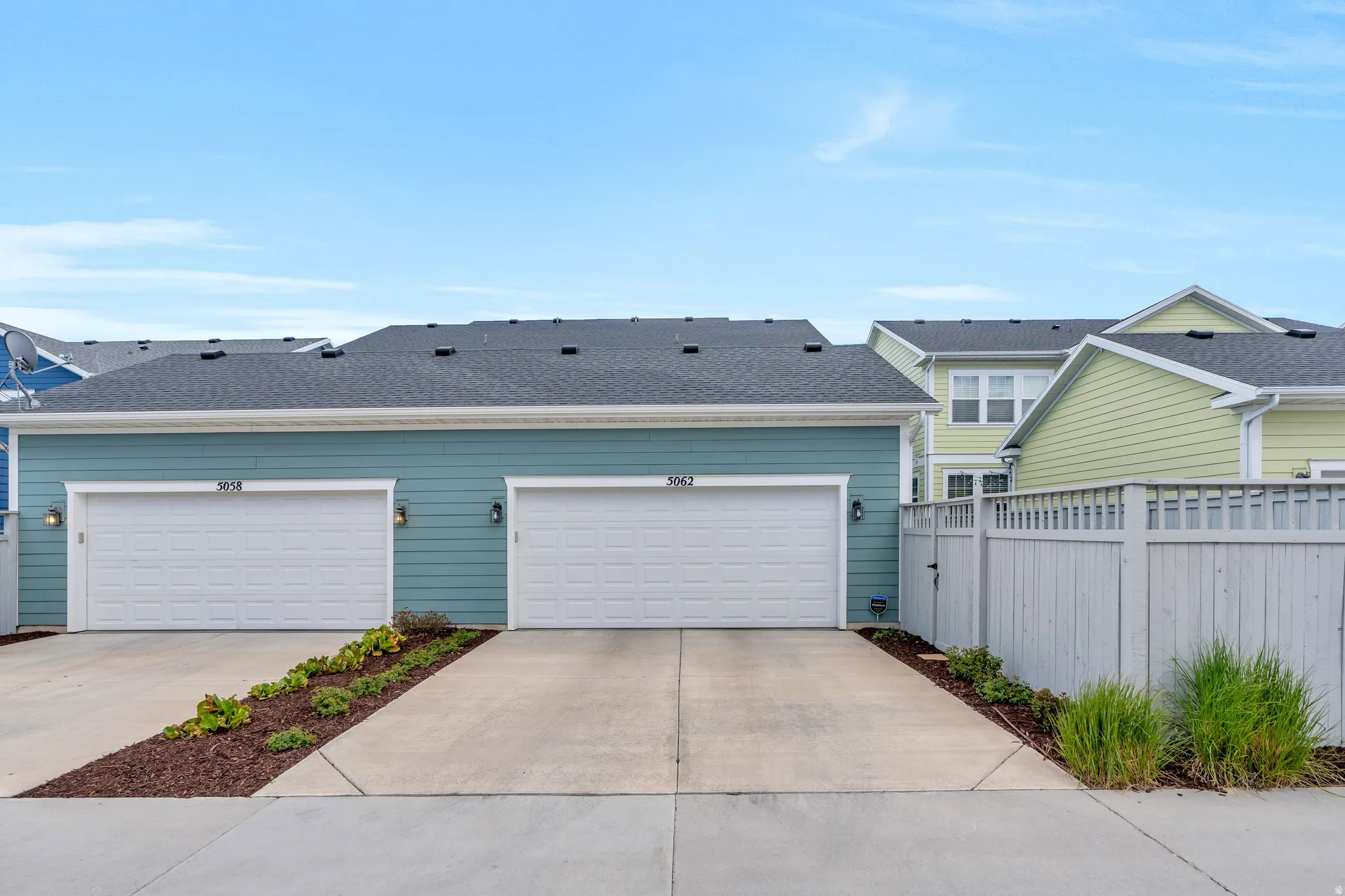 Teal siding exterior with white garage doors