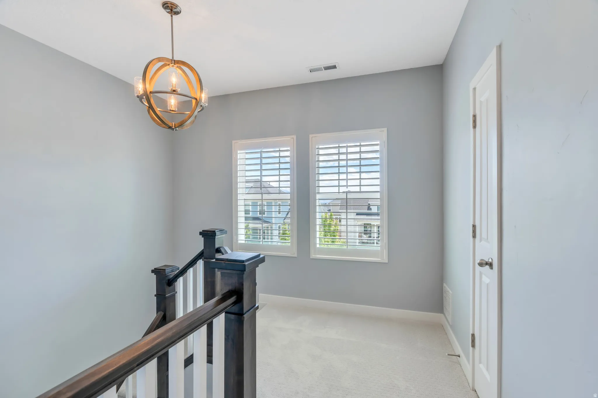 Upper-level landing featuring a contemporary chandelier with a wood-finish frame and glass shades