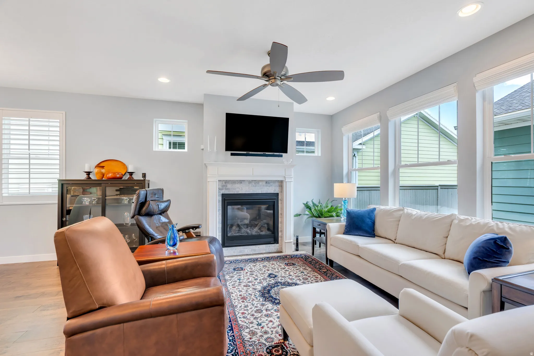 Living area featuring light wood-finish flooring and a central fireplace with a tiled surround and mantel