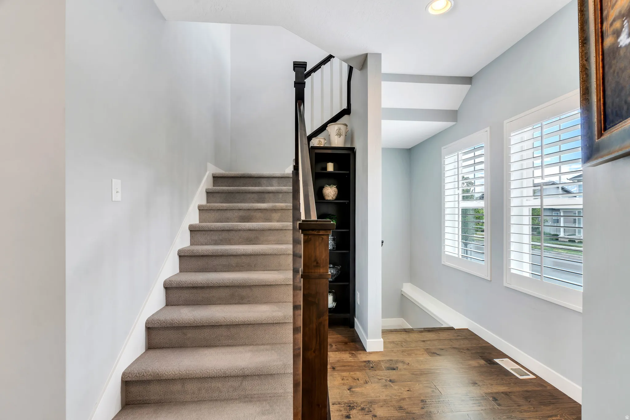 Carpeted staircase with dark wood newel post and balusters