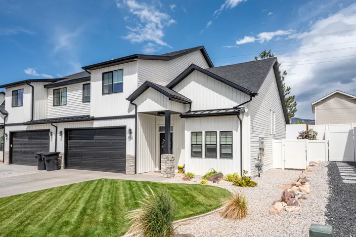 Modern white exterior with dark trim and black garage doors