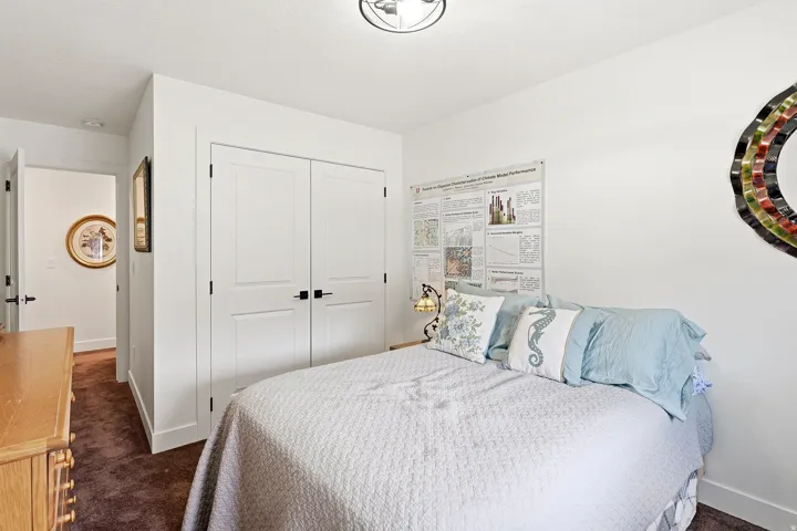 Bedroom featuring white walls, brown carpet, a flush-mount ceiling light fixture, and a double-door closet with black hardware