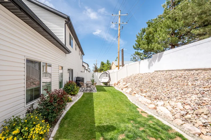 Private outdoor space featuring a manicured lawn, a concrete patio, and a low-maintenance rockscape