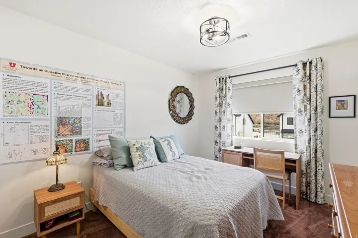 Bright bedroom with a window offering natural light, dark curtain rod, and patterned drapes