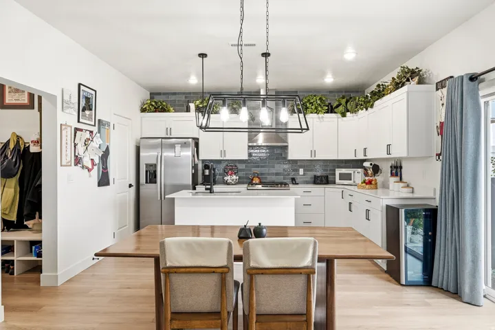 Gourmet kitchen with white cabinetry, stainless steel appliances, and a blue subway tile backsplash