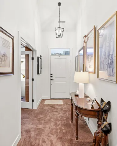 Entryway featuring a white paneled door with transom window, vaulted ceiling, and dark lantern pendant light