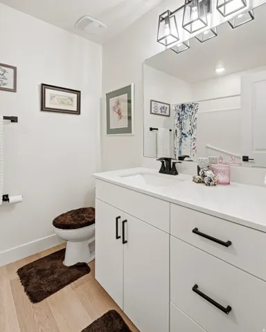 White vanity with a solid surface countertop, an undermount sink, and matte black fixtures