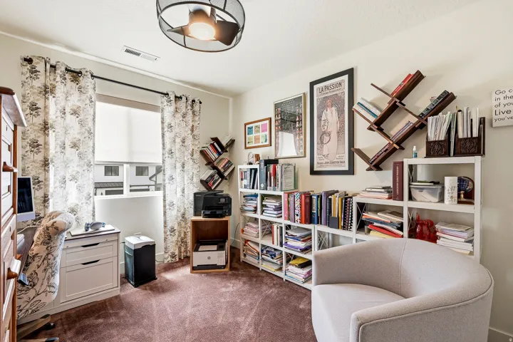 Spacious room featuring a single window with roller shade, overhead lighting with a ceiling fan, and carpeted flooring