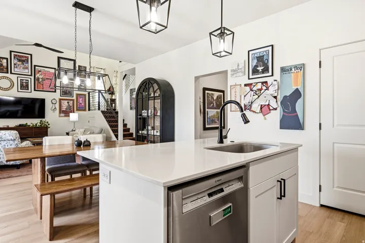 Kitchen island with a stainless steel sink and matte black faucet, integrated dishwasher, and white countertop