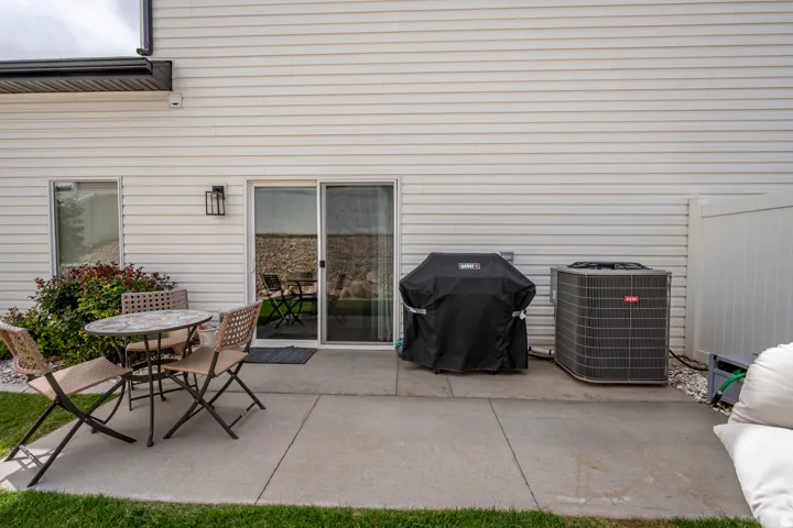 Rear patio featuring a concrete slab, sliding glass door entry, and white vinyl siding