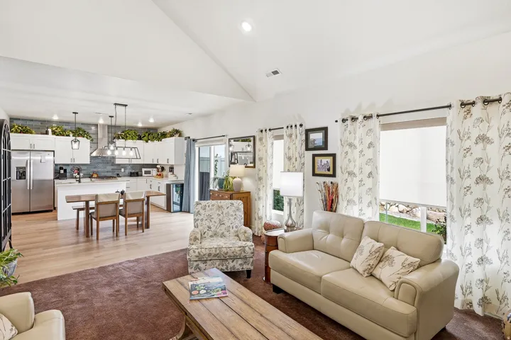 Vaulted ceilings enhance this open-concept living space, featuring wood-finish flooring and a central kitchen island