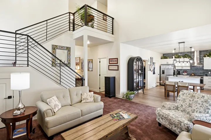 Two-story living area featuring a prominent staircase with black horizontal bar railing, an upper-level landing, and recessed lighting