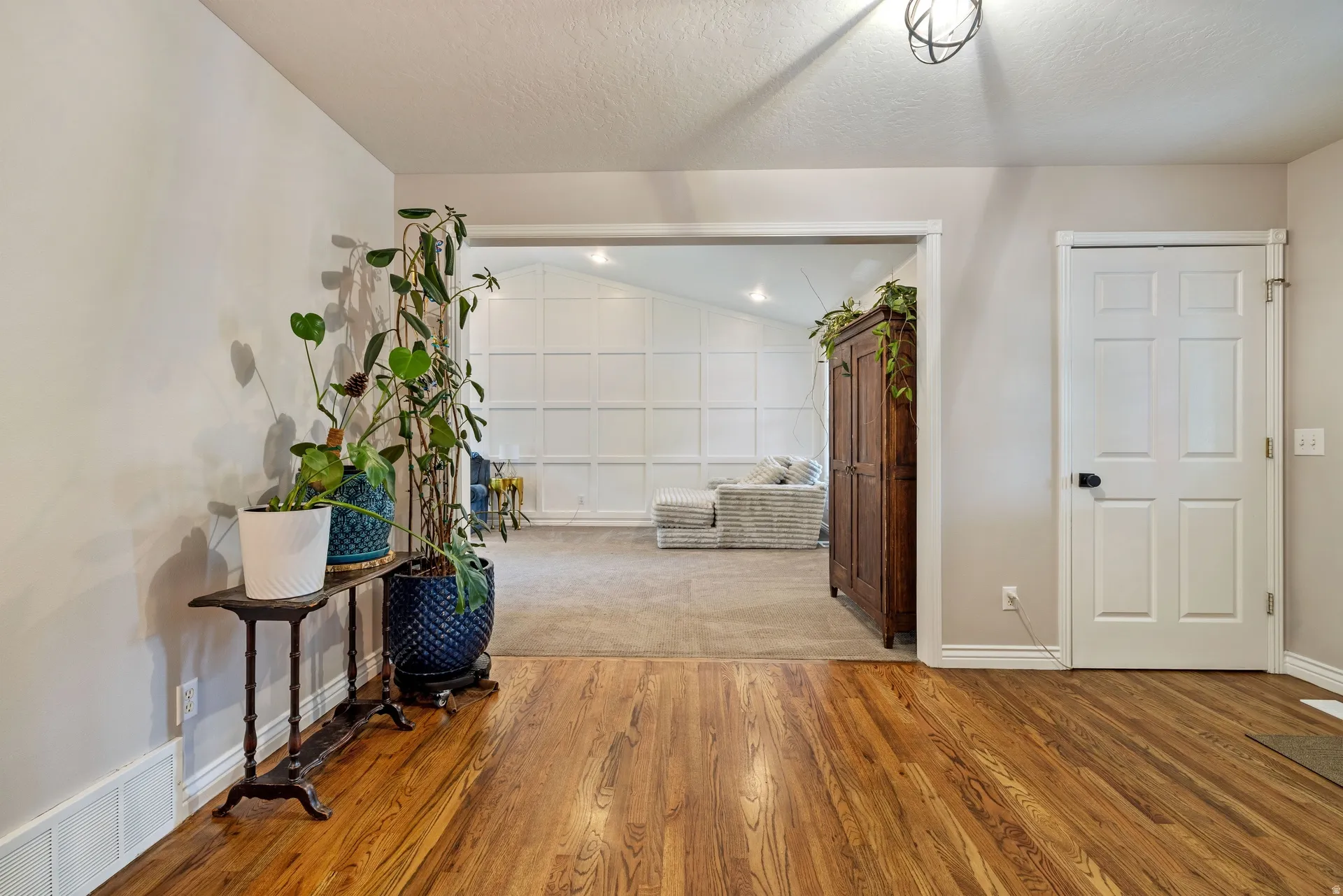 Hardwood-finish flooring extending into an open entryway, featuring a modern semi-flush mount ceiling light