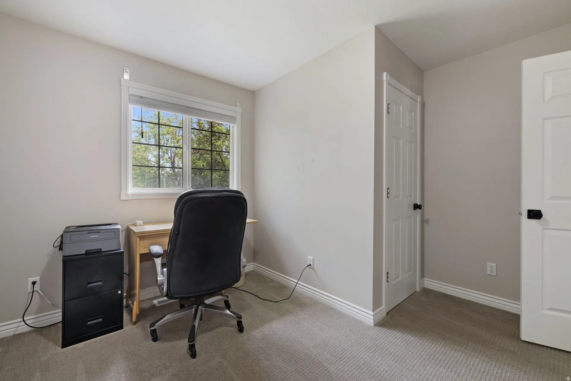 Carpeted room featuring a window with natural light, white trim, and two white panel doors with black hardware