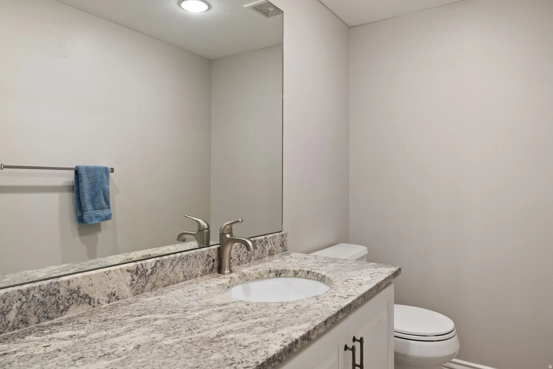 Bathroom featuring a white vanity with dark hardware, undermount sink, brushed nickel faucet, and a granite-finish countertop