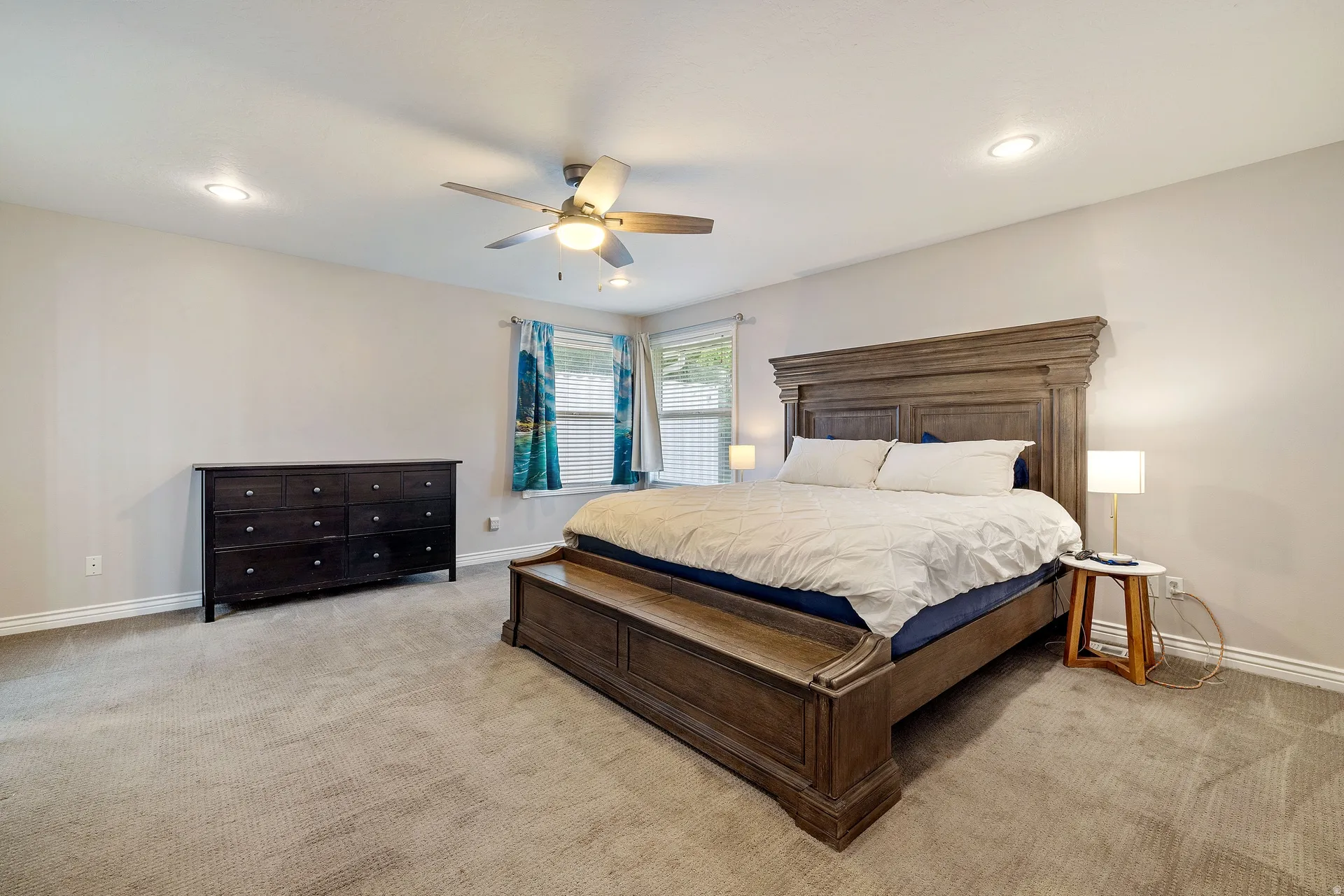 Spacious bedroom featuring light-colored walls, recessed lighting, and a ceiling fan