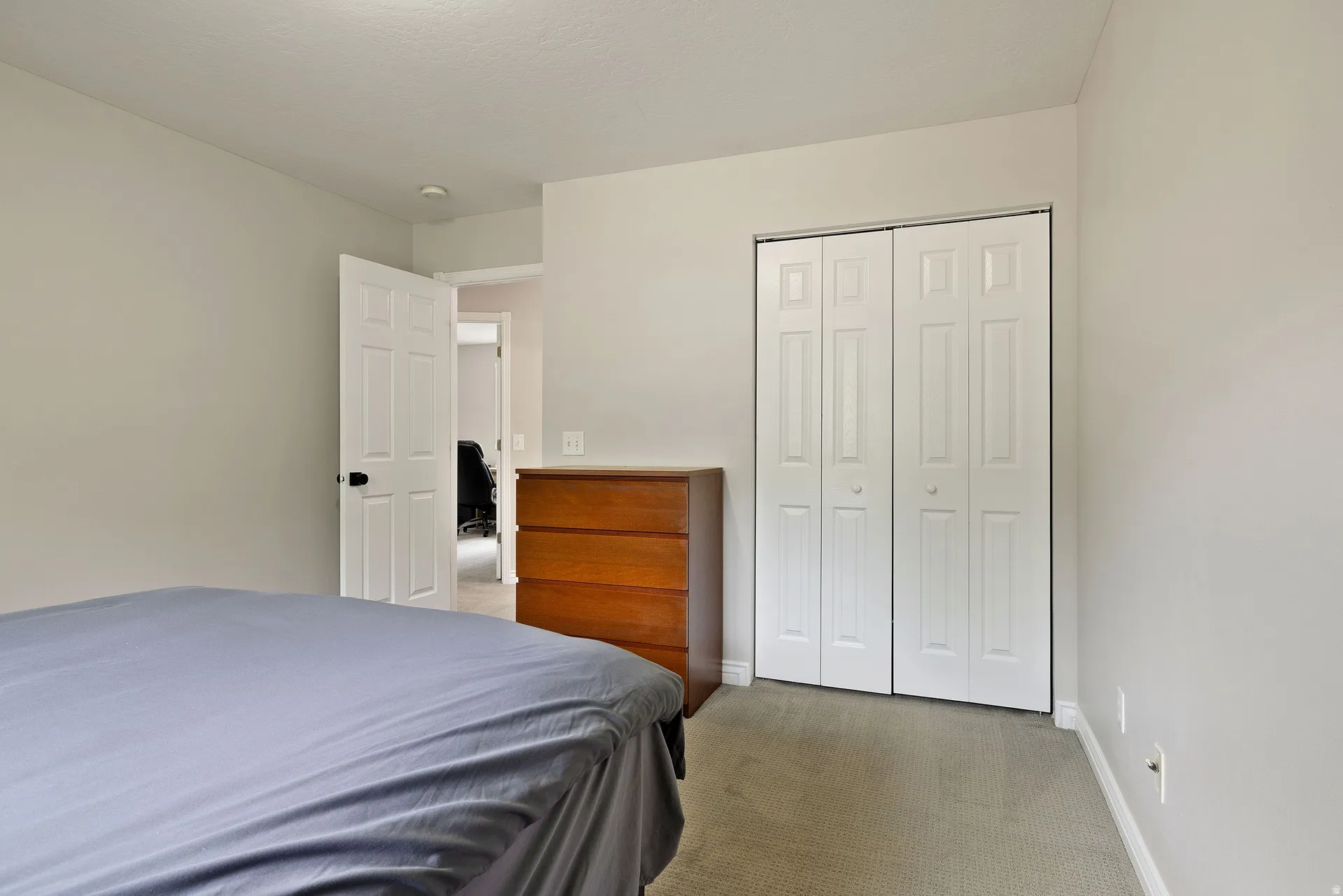 Neutral-toned interior room featuring light gray walls, plush gray carpeting, and white baseboards