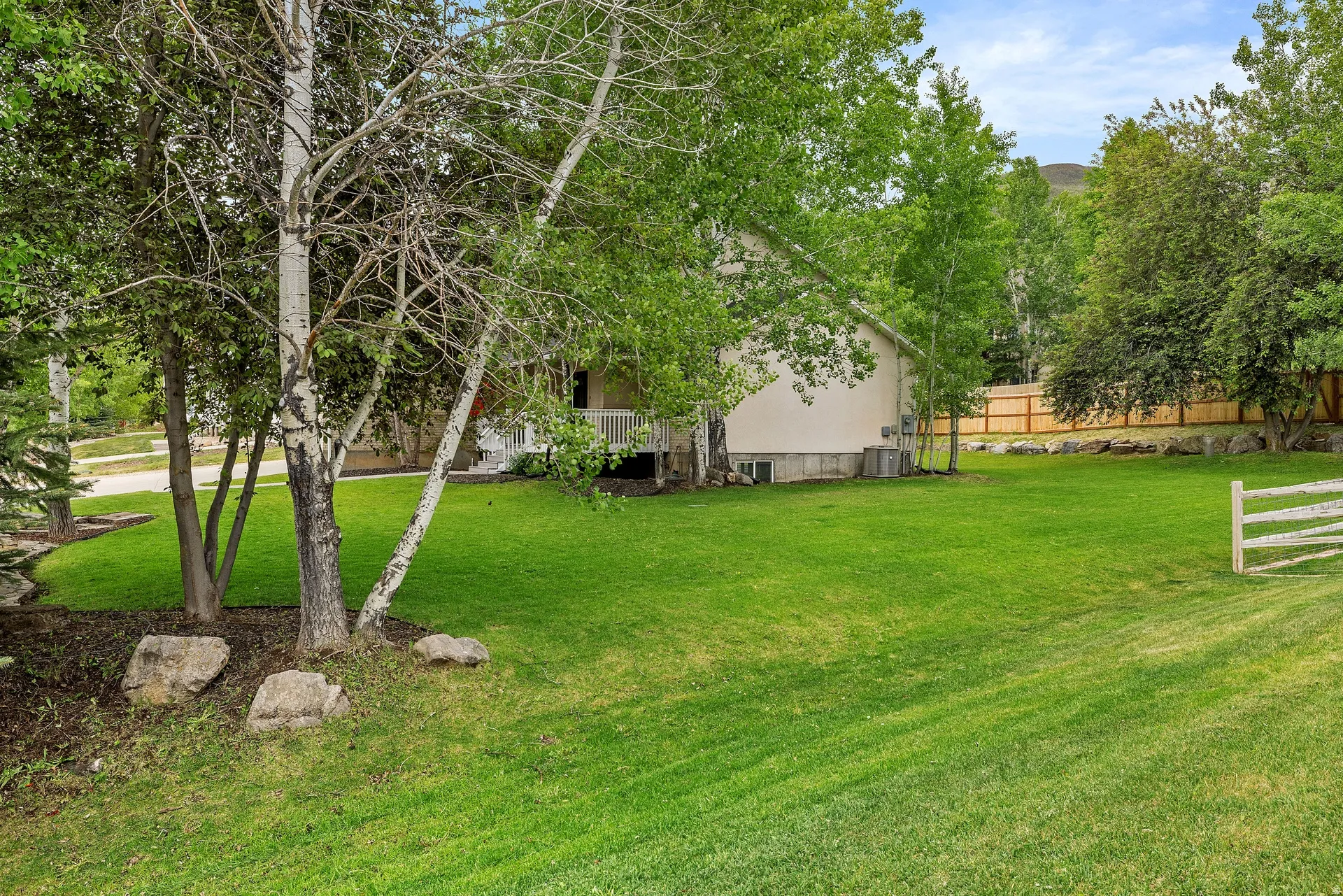Expansive green lawn with established trees and natural rock landscaping