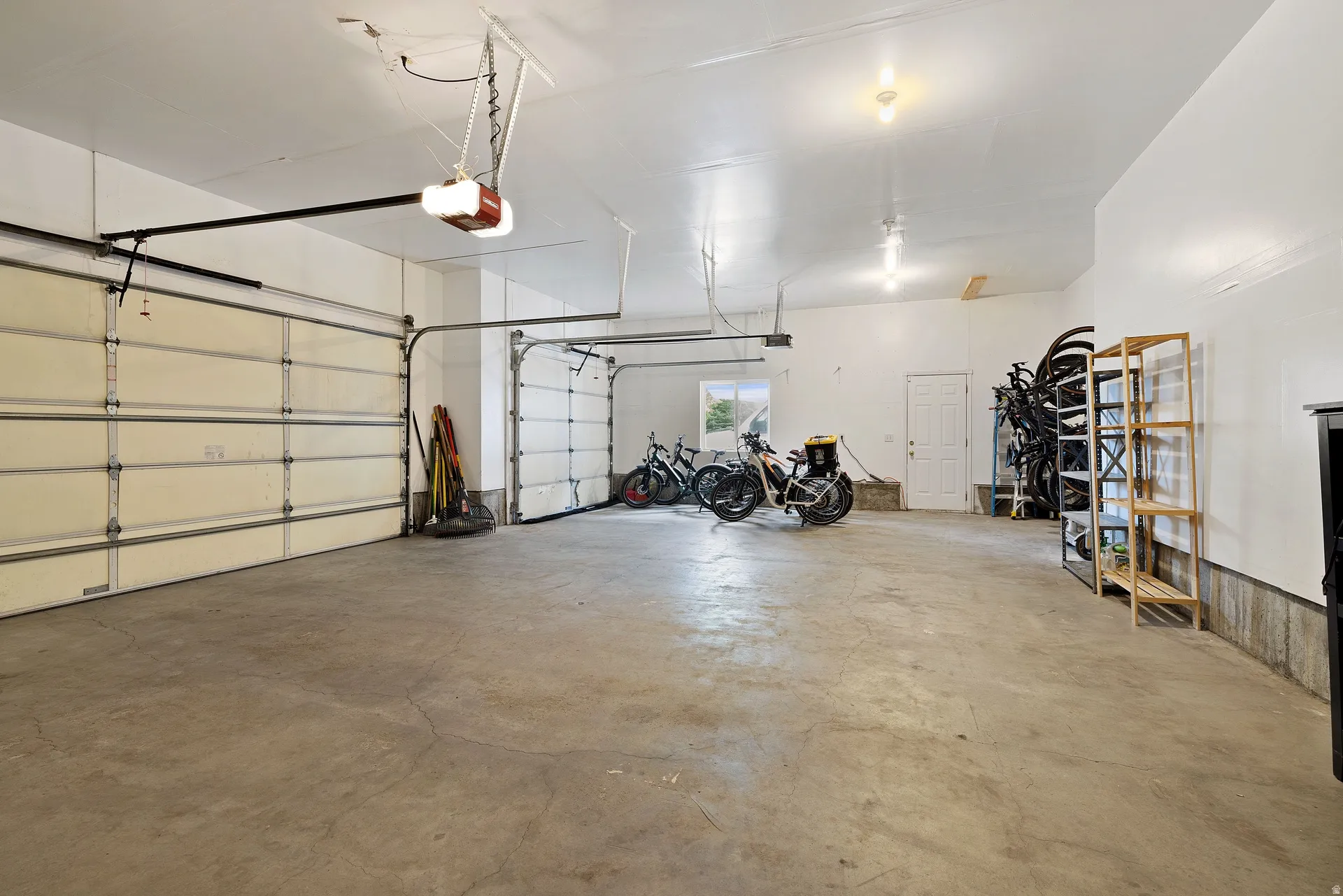 Spacious garage featuring two overhead doors, a concrete floor, and white painted walls