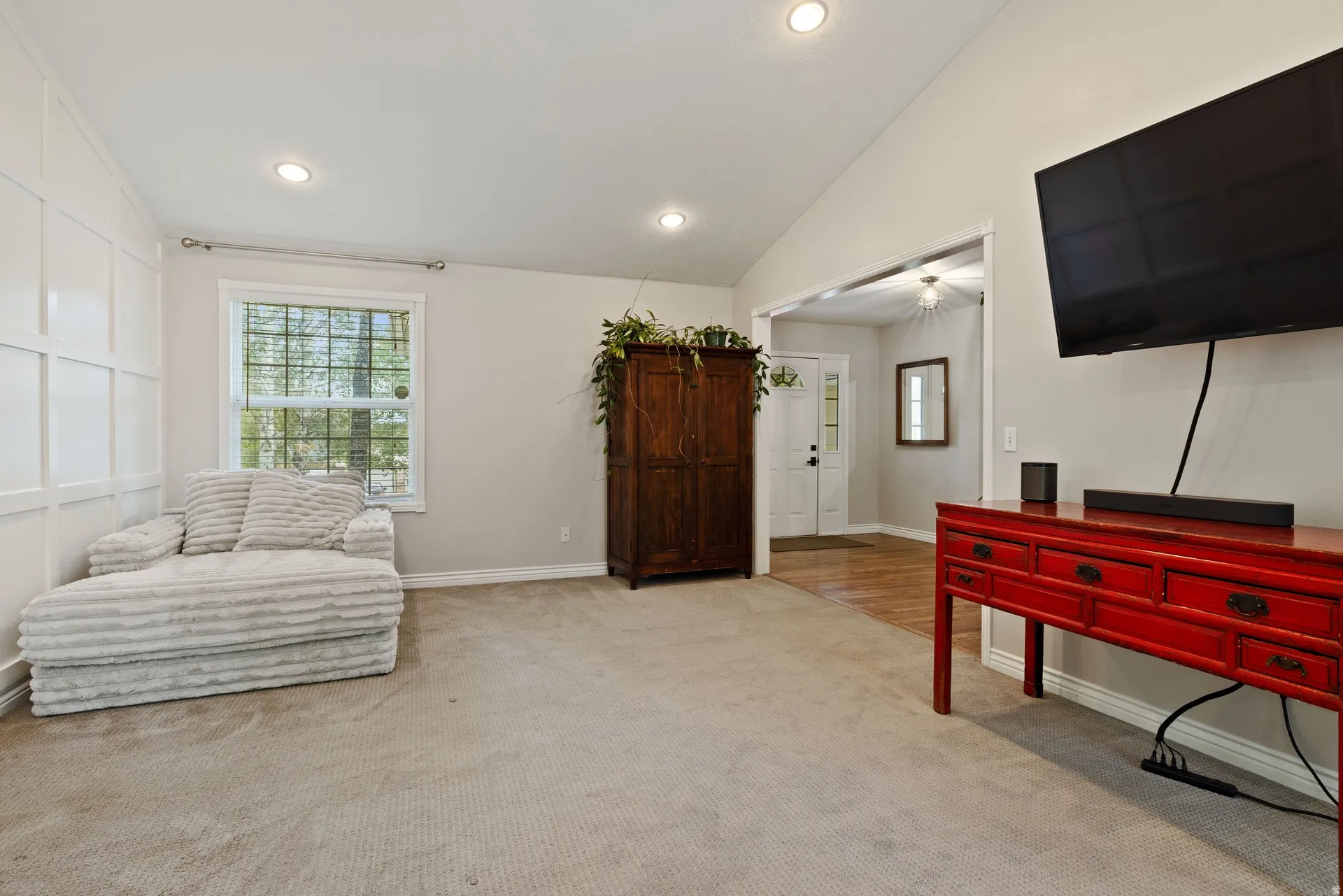 Spacious room featuring vaulted ceilings, recessed lighting, a grid accent wall, and a large window