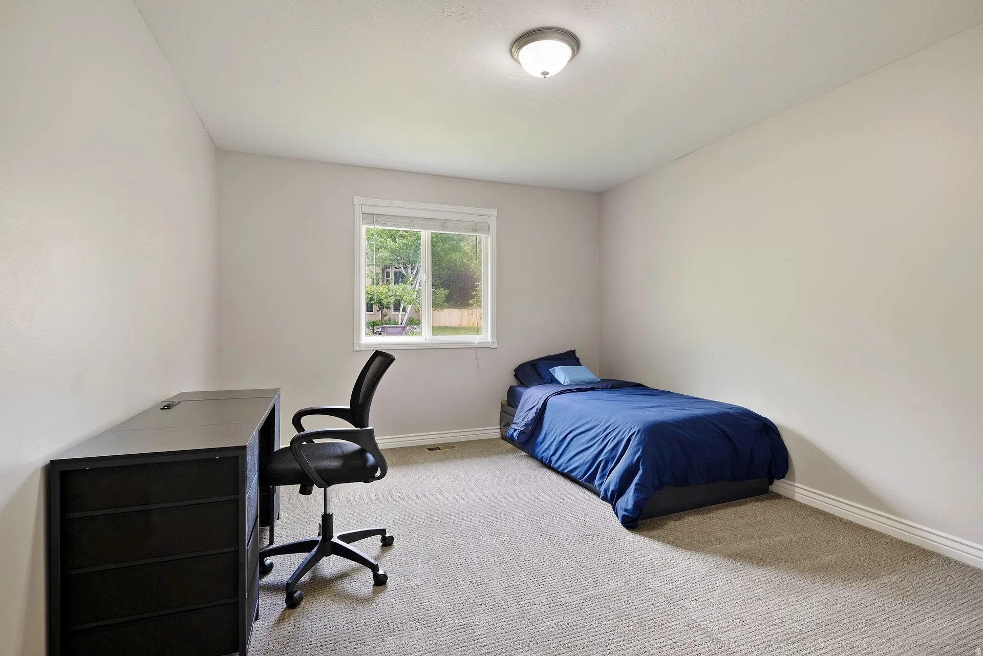 Bright room with a neutral color palette, featuring a window and carpeted flooring
