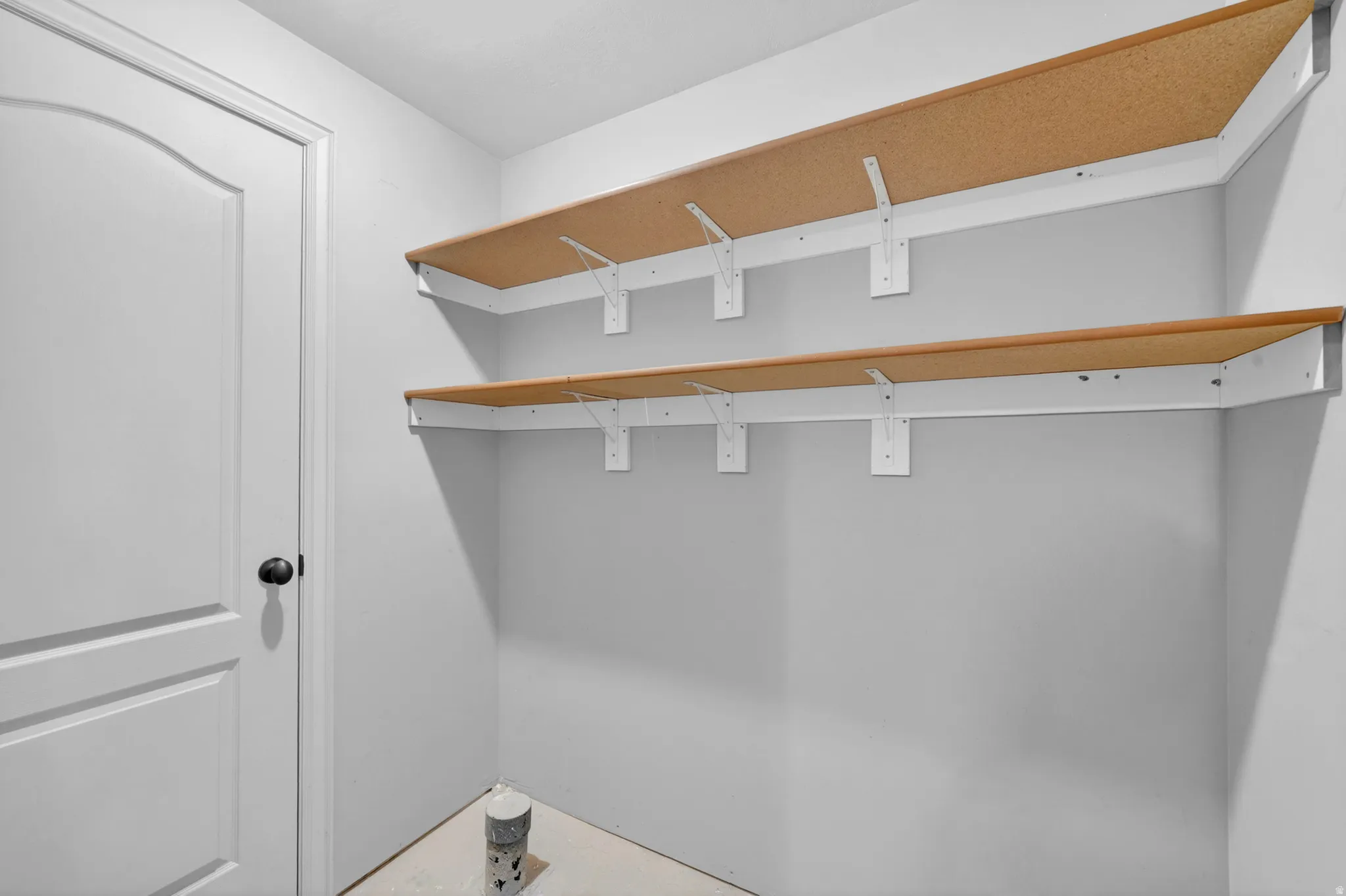 Corner shelving unit featuring two levels of wood-finish shelving with white brackets