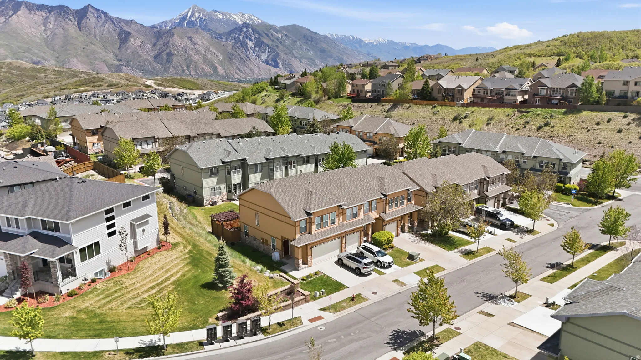 Expansive mountain range backdrop featuring residential properties, paved streets, and landscaped yards